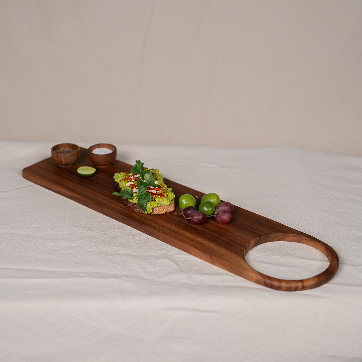 Handgefertigtes Teakholzbrett mit Loch – langes Schneide- & Servierbrett ca. 70x18x1,5 cm im rustikalen Design mit Brot und Früchten